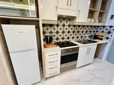 a kitchen with white cabinets and a stove top oven at 34 On The Den in Stellenbosch