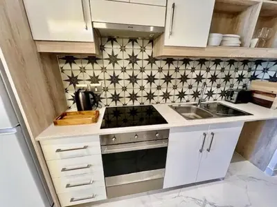 a kitchen with white cabinets and black and white tiles at 34 On The Den in Stellenbosch