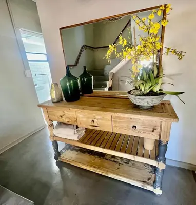 a mirror on top of a wooden table with flowers on it at The House Next Door in Stellenbosch