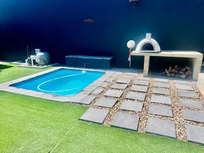 a swimming pool with a bench next to a blue wall at The House Next Door in Stellenbosch
