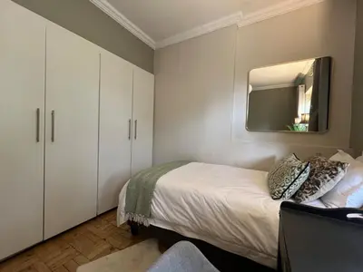 a bedroom with a bed and a mirror on the wall at The House Next Door in Stellenbosch