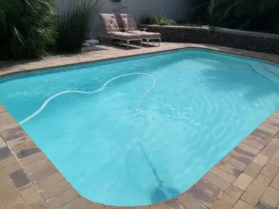 a large blue swimming pool with two chairs in a yard at Cosy en-suite room Stellenbosch in Stellenbosch