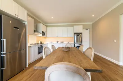 a kitchen with a wooden table and white cabinets at 68 LErmitage Elegant Mountain Apartment in Franschhoek