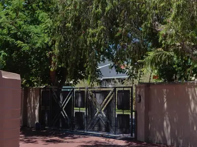 a black gate with a tree in front of a house at Julinas Guesthouse in Panorama