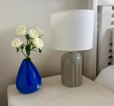 a table with a lamp and a blue vase with white roses at Little Haven in Kenridge