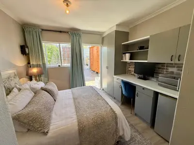 a bedroom with a bed and a desk and a window at Courtyard Hideaway in Kenridge