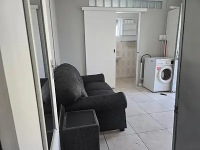a living room with a couch and a washing machine at Cozy home away from home in Cape Town