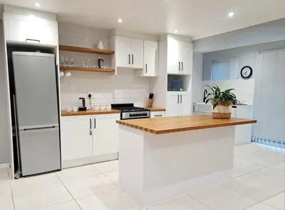 a kitchen with white cabinets and a refrigerator at Mooiloop Self Catering in Bellville