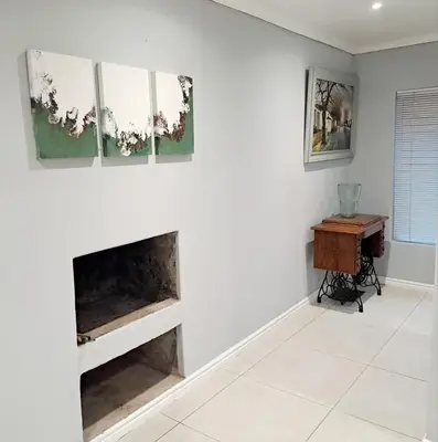 a living room with a fireplace and a desk at Mooiloop Self Catering in Bellville