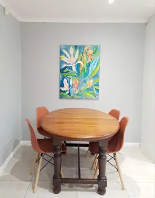 a wooden table with chairs and a painting on the wall at Mooiloop Self Catering in Bellville