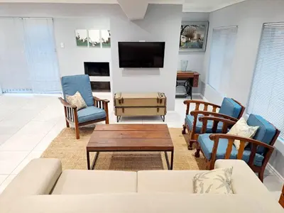 a living room with a couch and chairs and a tv at Mooiloop Self Catering in Bellville