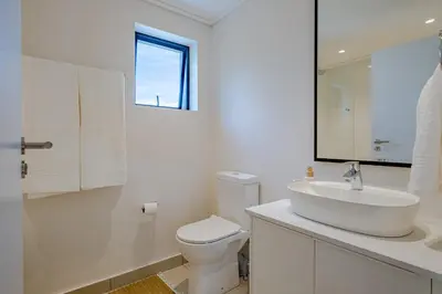 a white bathroom with a sink and a toilet at Whale Melody Love Hermanus in Hermanus