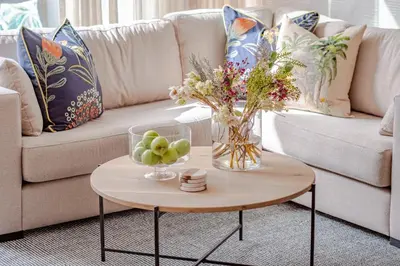 a vase of flowers on a table in front of a couch at Whale Melody Love Hermanus in Hermanus