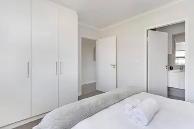 a white bedroom with white cabinets and a bed at Chic 1 bedroom apt in Century city in Cape Town