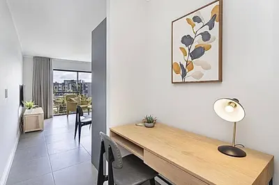 a living room with a wooden table and a dining room at Chic 1 bedroom apt in Century city in Cape Town