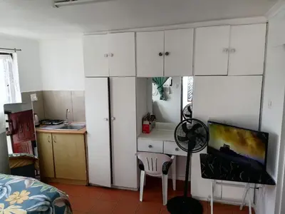 a kitchen with white cabinets and a chair in a room at 72 the trout H lodge in Goodwood
