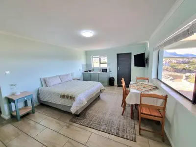 a bedroom with a bed and a table and chairs at Thalassa in Bettyʼs Bay