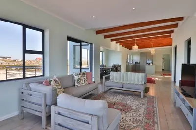 a living room with a couch and chairs and a television at Thalassa in Bettyʼs Bay