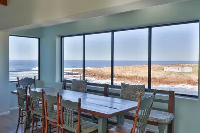 a dining room with a table and chairs and the ocean at Thalassa in Bettyʼs Bay