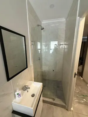 a white bathroom with a shower and a sink at Table Mountain View Apartment in Cape Town