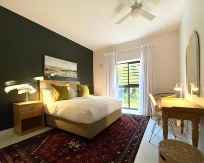 a bedroom with a bed and a desk and a window at Bosch & Bloom in Stellenbosch