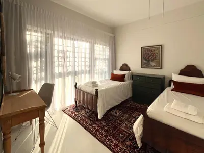 a bedroom with two beds and a desk and a window at Bosch & Bloom in Stellenbosch