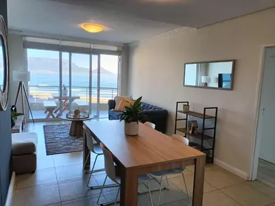 a living room with a table and a couch at Beautiful 2 Bedroom Apartment with Ocean Views, Bloubergstrand in Cape Town