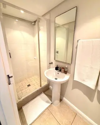 a white bathroom with a sink and a shower at Beautiful 2 Bedroom Apartment with Ocean Views, Bloubergstrand in Cape Town