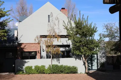 a white building with a tree in front of it at Gilgal Guest Accommodation in Onder-Papegaaiberg