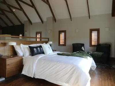 a bedroom with a large white bed and a chair at Gilgal Guest Accommodation in Onder-Papegaaiberg