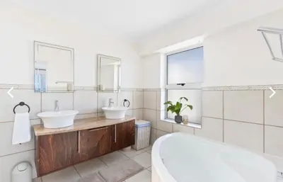 a bathroom with a tub and a toilet and a sink at The Continental Sea Spray in Cape Town