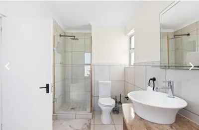 a bathroom with a sink and a toilet and a shower at The Continental Sea Spray in Cape Town