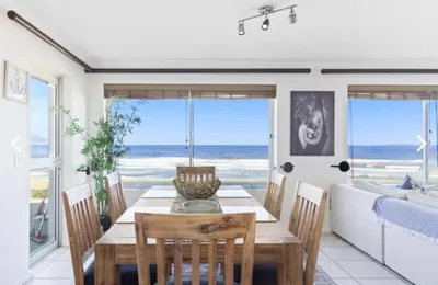 a dining room with a table and chairs and the ocean at The Continental Sea Spray in Cape Town
