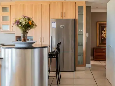 a kitchen with a stainless steel refrigerator and a table at Shores Keep - Self Catering Home in Hermanus