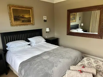 a bedroom with a large bed and a mirror at Shores Keep - Self Catering Home in Hermanus