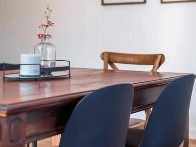 a wooden table with chairs and a vase with flowers at Atticus Self Catering Accommodation in Cape Town