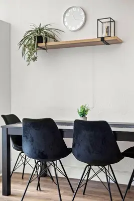 a table with three chairs and a clock on a wall at Atticus Self Catering Accommodation in Cape Town