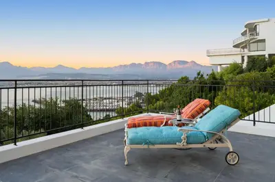 a chair on a balcony with a view of the water at Suikerbossie 52 in Cape Town