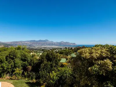 a view of the ocean from a hill with trees at 5 Rembrandt Guesthouse in Somerset West