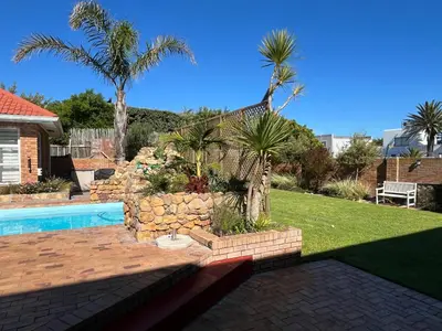 a backyard with a swimming pool and palm trees at Sunset Breeze in Cape Town