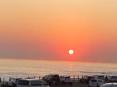 a sunset over the ocean with cars parked on the beach at Sunset Breeze in Cape Town