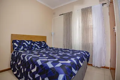 a blue and white bed in a room with a window at Wilcuma Lodge in Plattekloof