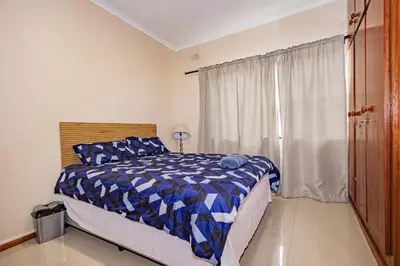 a bedroom with a bed with a blue comforter and a window at Wilcuma Lodge in Plattekloof