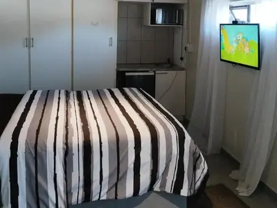 a bedroom with a striped bed with a television on at Eneco Lodge in Cape Town