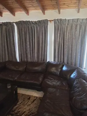 a leather couch in a living room with curtains at Halibut Suite in Strand