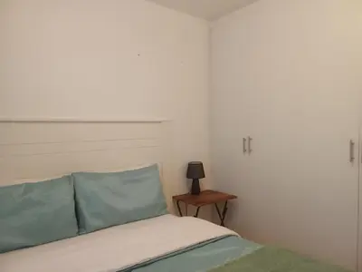 a bedroom with a bed with blue pillows and a table at Klipkop Self-catering Haven in Cravenby