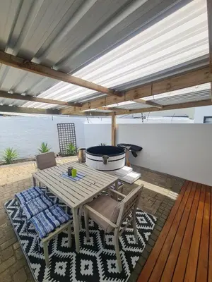 a patio with a table and chairs on a deck at Spring Tide Beach Flat Child Petfriendly Hot Tub in Bloubergstrand