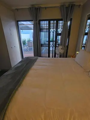 a large bed in a room with a large window at Spring Tide Beach Flat Child Petfriendly Hot Tub in Bloubergstrand