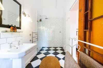 a bathroom with a white sink and a black and white floor at Bramley Cottage, Cheverells Farm in Grabouw
