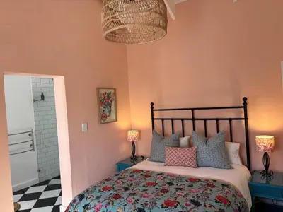 a bedroom with a bed with pink walls and a checkered floor at Bramley Cottage, Cheverells Farm in Grabouw